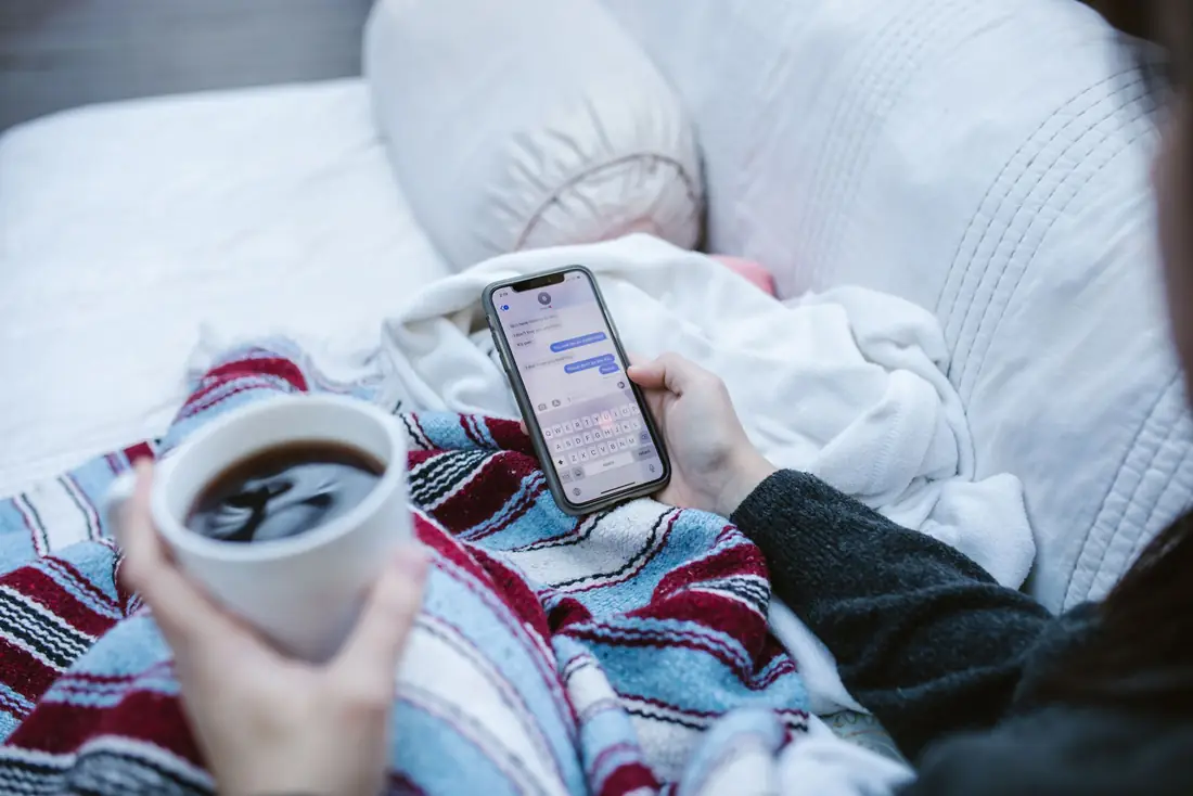 Someone reading on their phone with a cup of coffee