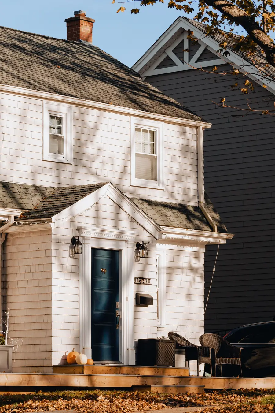 A white house with pumpkins on the front porch
